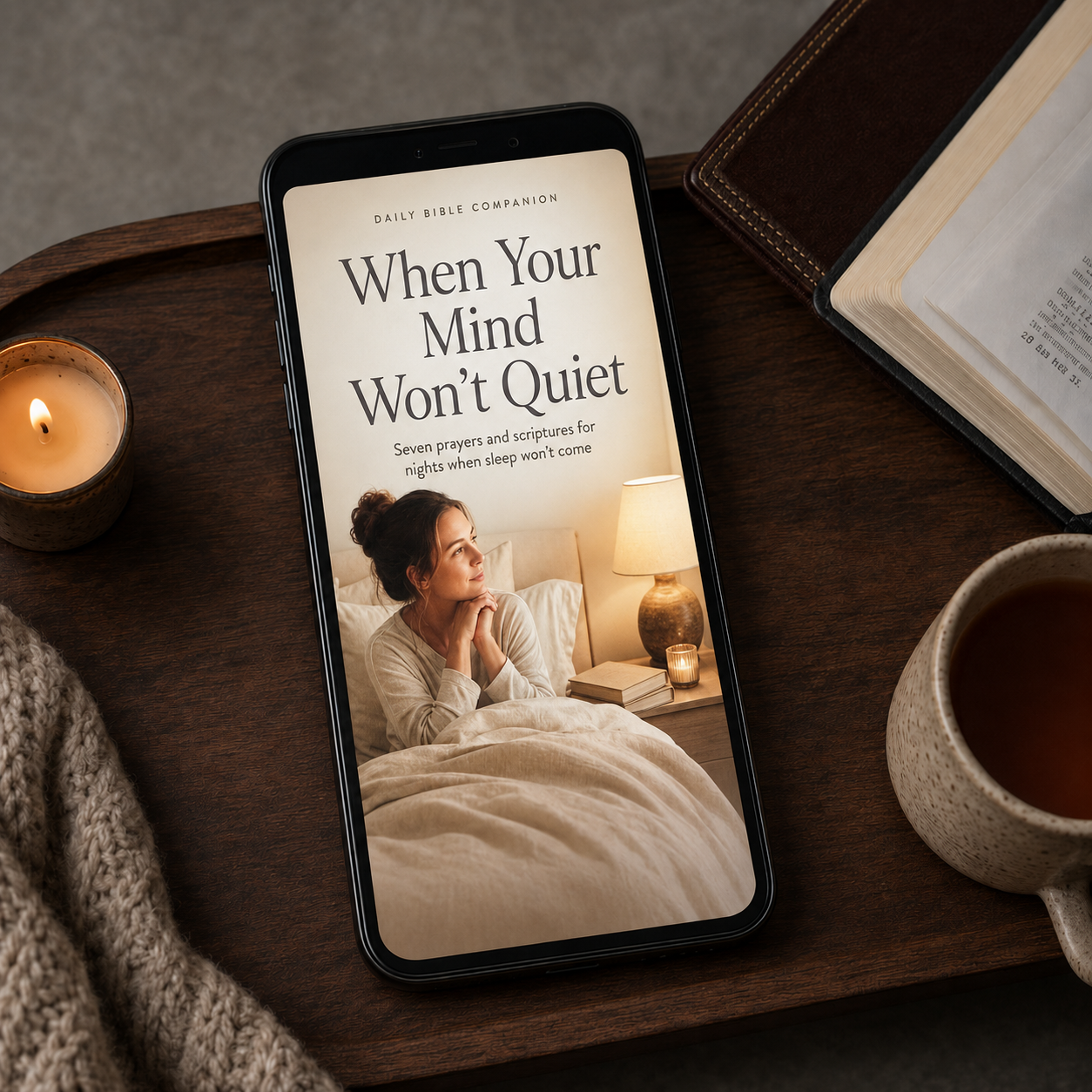 When Your Mind Won’t Quiet digital prayer guide displayed on a smartphone beside a Bible, tea, candle, and knit blanket.